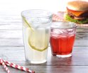 Deux verres, l'un avec de la limonade et une tranche de citron, l'autre avec une boisson rouge, avec des pailles rayées.