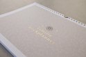 Familie weekplanner met gouden tekst en bladerpatroon op een beige achtergrond.