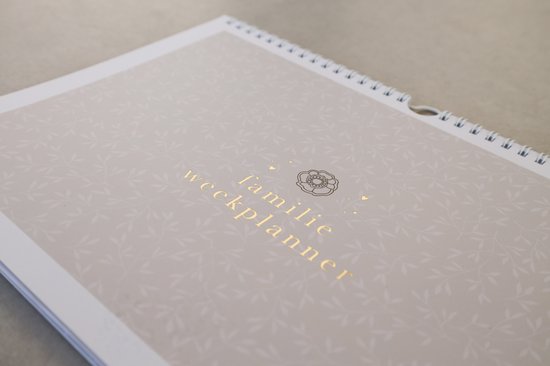 Familie weekplanner met gouden tekst en bladerpatroon op een beige achtergrond.