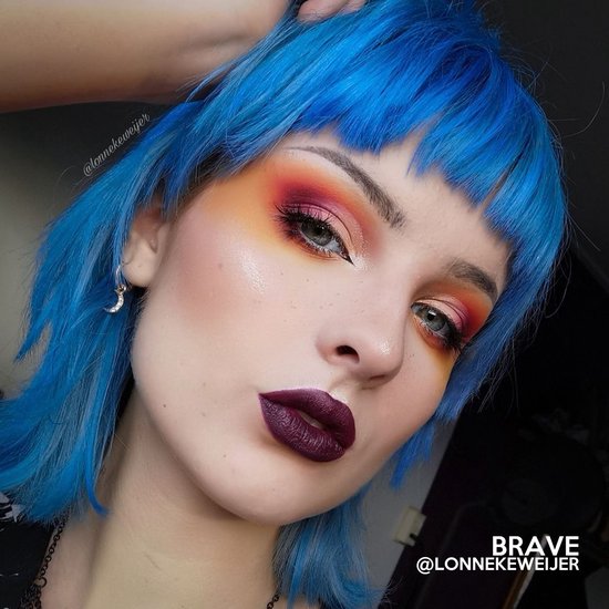 Model met felblauw gemutst kapsel en dramatische oog- en lipmake-up, met de tekst 'Brave' en '@lonnekeweijer'.