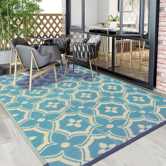 Grand tapis réversible turquoise et crème sur un balcon, avec des meubles.