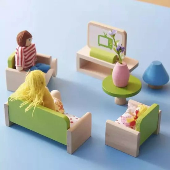 Houten poppen in een miniatuur woonkamer. Twee poppen zitten in groene banken, een pop ligt in een bedje, een tv en tafeltje staan op de achtergrond.