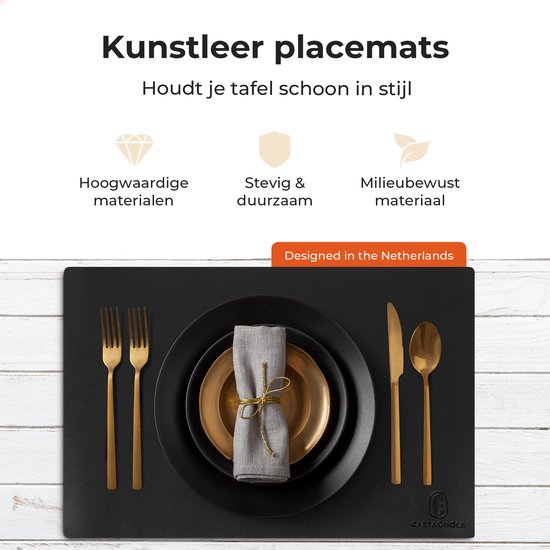 Set de table noir sur fond de bois blanc, dressé avec des couverts dorés et de la vaisselle.