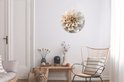 Wandcirkel met witte dahlia met beige midden, in een lichte woonkamer.