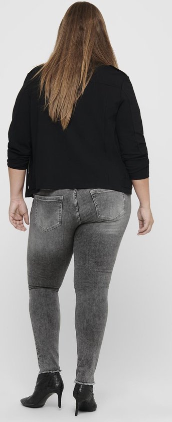 Model van achteren gezien in een zwarte jas en grijze skinny jeans met rafelige zoom.