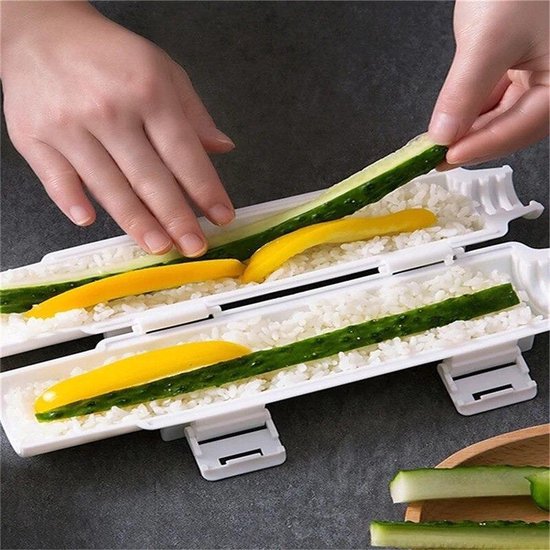 Handen vullen een witte sushi-maker met rijst en vullen aan met stukjes komkommer en gele paprika.
