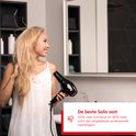 Vrouw met blond haar droogt haar haar met een Solis föhn in een badkamer.