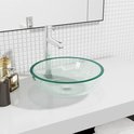 Lavabo en verre teinté vert clair sur un plan de travail blanc avec un robinet argenté.