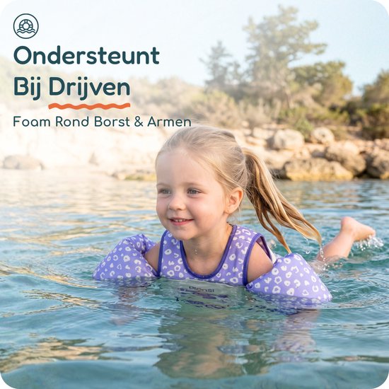 Meisje met een zwemvest met panterprint, drijvend in blauw water, met achtergrond van rotsen en bomen.