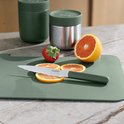 BergHOFF kartelmes met groen handvat, gebruikt om sinaasappelschijfjes te snijden op een groen snijplank.