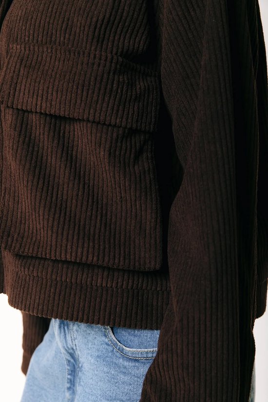Detail van de opgestikte zakken op een bruine corduroy jas.