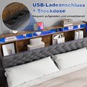 Hoofdbord van donkergrijs gestoffeerd bed met houten legplanken, LED-verlichting en USB-laadpunten en stopcontact.