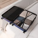 Open donkerblauwe koffer op een bed, gevuld met nette kleding.