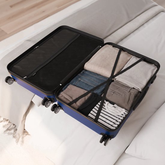 Open donkerblauwe koffer op een bed, gevuld met nette kleding.