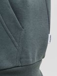 Close-up van het witte 'JACK&JONES'-label aan de zijkant van een donkergroene hoodie.