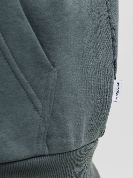 Close-up van het witte 'JACK&JONES'-label aan de zijkant van een donkergroene hoodie.
