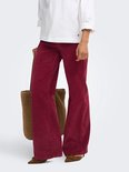 Model dat loopt in bordeauxrode corduroy broek met wijde pijpen en witte top.