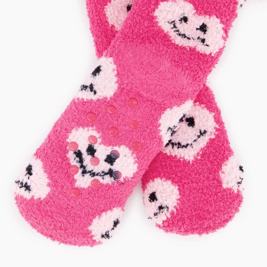 Zool van roze, pluizige huissokken met roze antislipstippen en een patroon van lachende hartjes.