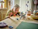 Fille joyeuse tenant un chat LEGO avec un jouet orange, table avec des pièces.