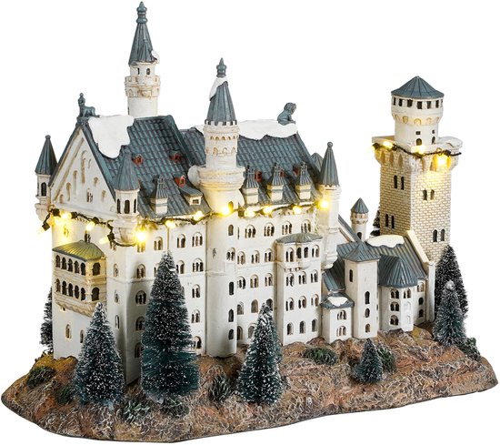 Miniature blanche du château de Neuschwanstein avec guirlandes lumineuses et sapins.