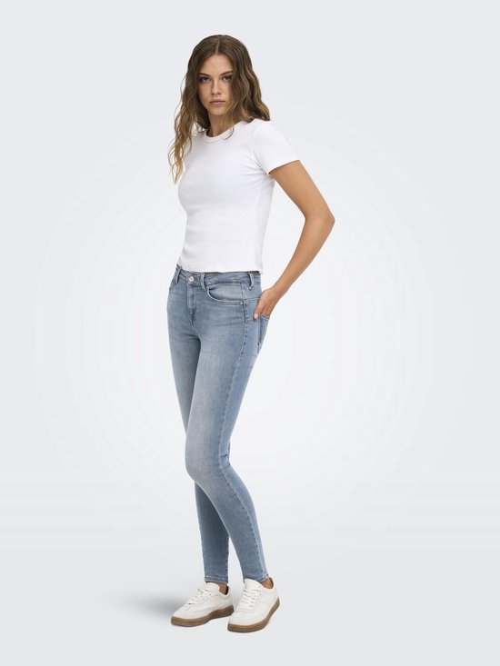 Model draagt een lichtblauwe ONLY skinny jeans, gecombineerd met een wit T-shirt en sneakers.