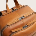 Bovenaanzicht van een bruine leren rugzak met meerdere ritsen en The Chesterfield Brand branding.