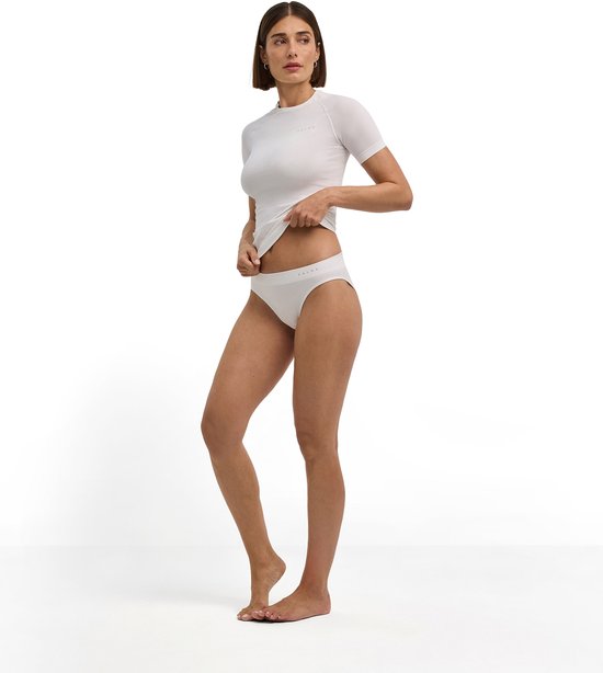 Model in een wit FALKE functioneel sportsetje, bestaande uit een shirt met korte mouwen en een sportslip.