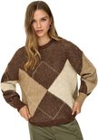 Model draagt een bruine, beige en crème gemêleerde gebreide trui met ruitpatroon en ronde hals, gecombineerd met een groene broek.