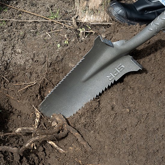 Voet in zwarte laars en hand in oranje-grijze handschoen gebruiken SPR spade om wortels in de aarde uit te graven.