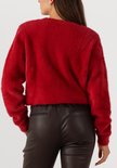 Een rode, pluizige trui met lange mouwen, gedragen door een model met haar handen in de broekzakken van een zwarte leren broek.