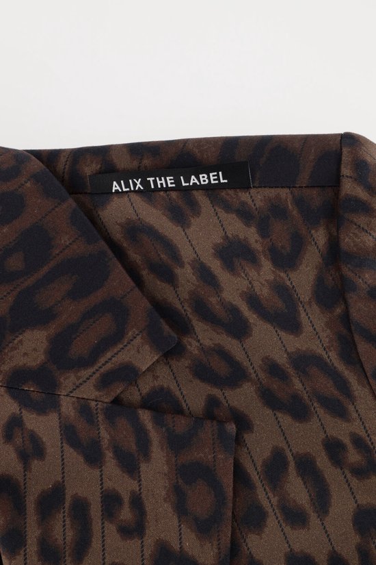 Close-up van kraag met zwart ALIX THE LABEL label op een bruine blazer met luipaardprint.