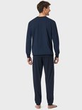 Achterkant van een man in een donkerblauwe pyjamaset met ruitpatroon op de top.