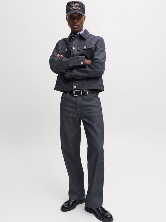 Model met gekruiste armen in een donkerblauw denim jack en bijpassende straight fit jeans.