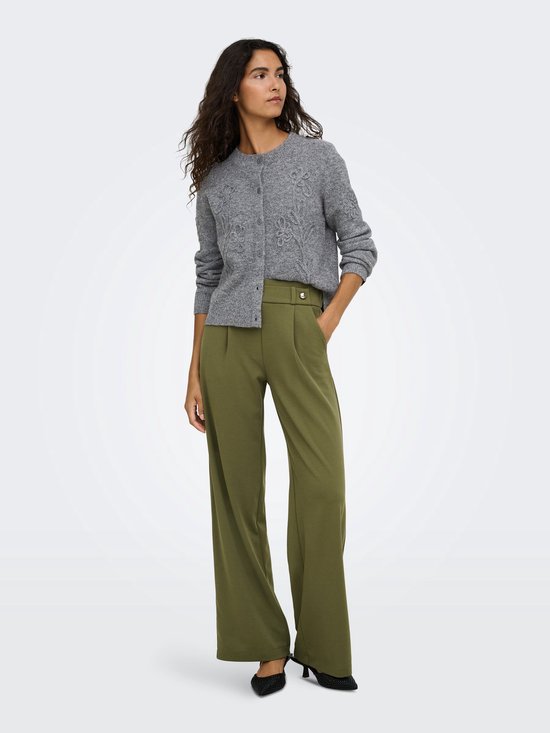 Model draagt een grijs vest met bloemdetails en een olijfgroene broek met wijde pijpen.