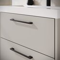 Detailopname van de twee beige lades met horizontale zwarte handgrepen op een hangend badkamermeubel.