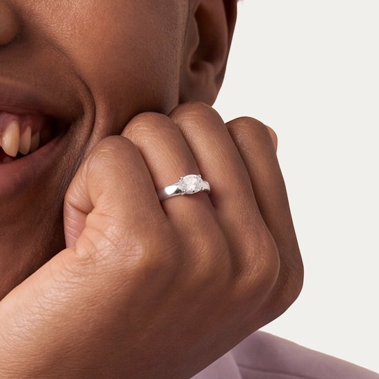 Close-up van een glanzende zilverkleurige roestvrijstalen ring met een heldere zirkonia om de vinger van het model.