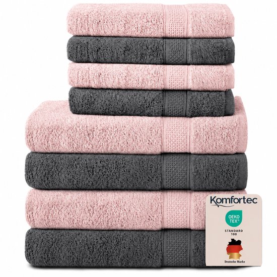 Pile de huit serviettes en rose et anthracite. Les serviettes ont une texture douce et un bord décoratif.