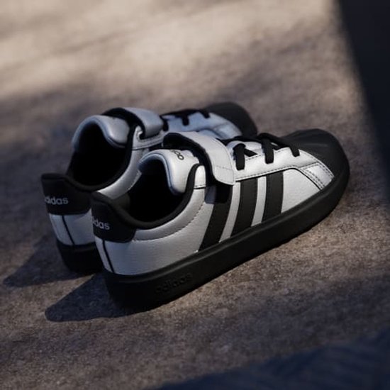 Zilveren Adidas sneakers met zwarte strepen en klittenbandsluiting. Zwarte neuzen en zolen.