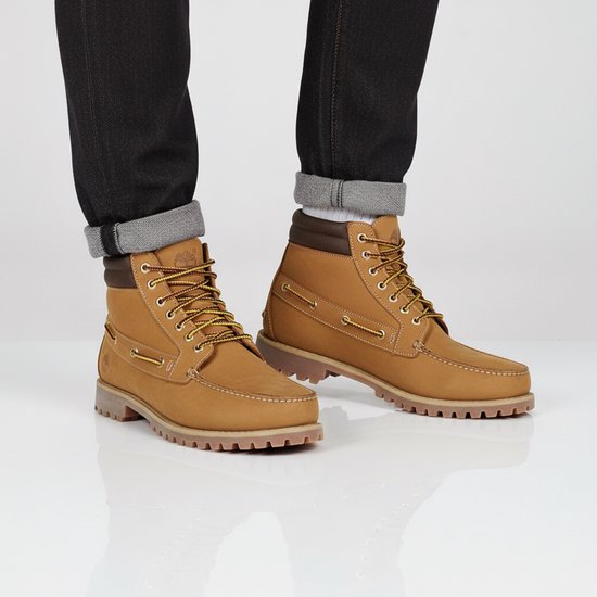 Homme en jean noir et chaussettes blanches porte des bottines à lacets Timberland marron avec des lacets jaunes et bordeaux.