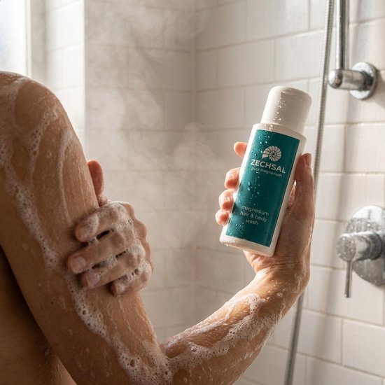 Hand die een Zechsal magnesium hair & body wash fles vasthoudt, met een handdoek.