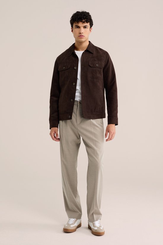 Man met donkerbruine suède jas, wit T-shirt en beige pantalon.