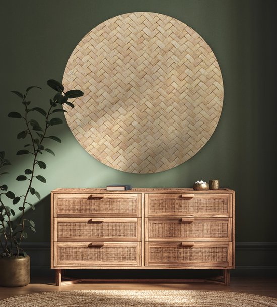 Décoration murale ronde en rotin avec motif tressé, au-dessus d'une commode en bois avec des détails en rotin.