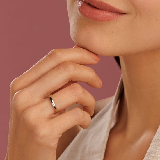 Gouden aanschuifring gedragen op een hand, close-up van de lippen en kin.
