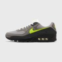 Zijenaanzicht van een grijze Nike Air Max 90 sneaker met neon groene Nike 'swoosh' en zwarte zool.