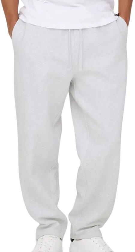 Man met handen in de zakken, draagt een grijze joggingbroek met trekkoord.