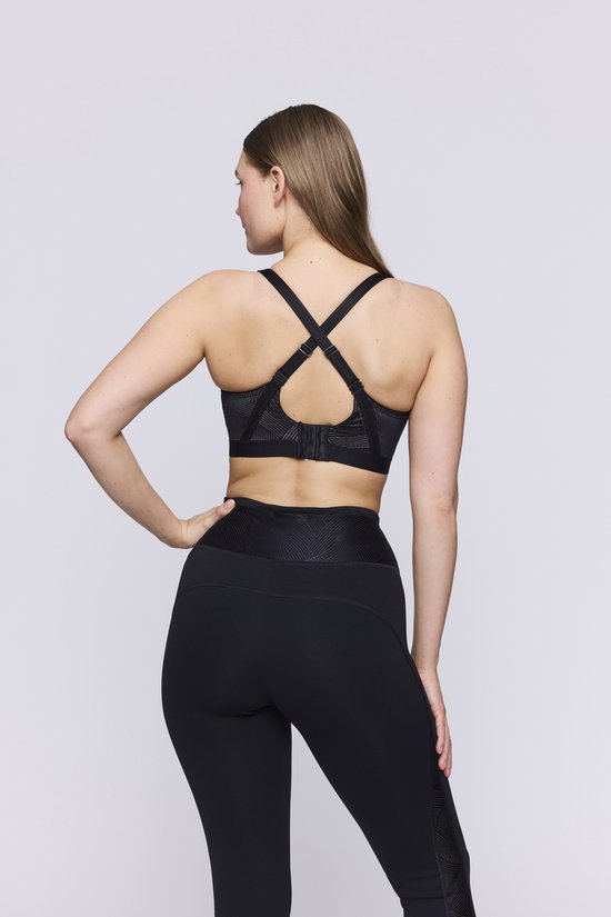 Model van achteren in een zwarte sportbeha met gekruiste bandjes en legging.