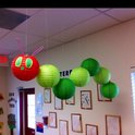 Een decoratie van een rups gemaakt van een rode lampion met groene en roze details, gevolgd door groene lampionnen.
