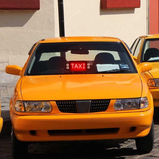 Gele taxi met een rood oplichtend 'TAXI'-bord boven de voorruit.