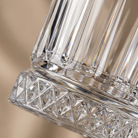 Detail van de gegroefde onderkant van een glazen whiskeyglas met een complexe geometrische print.