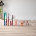Transparante pastel gekleurde Connetix magnetische tegels vormen een balbaan met gekleurde ballen, op een houten vloer.
